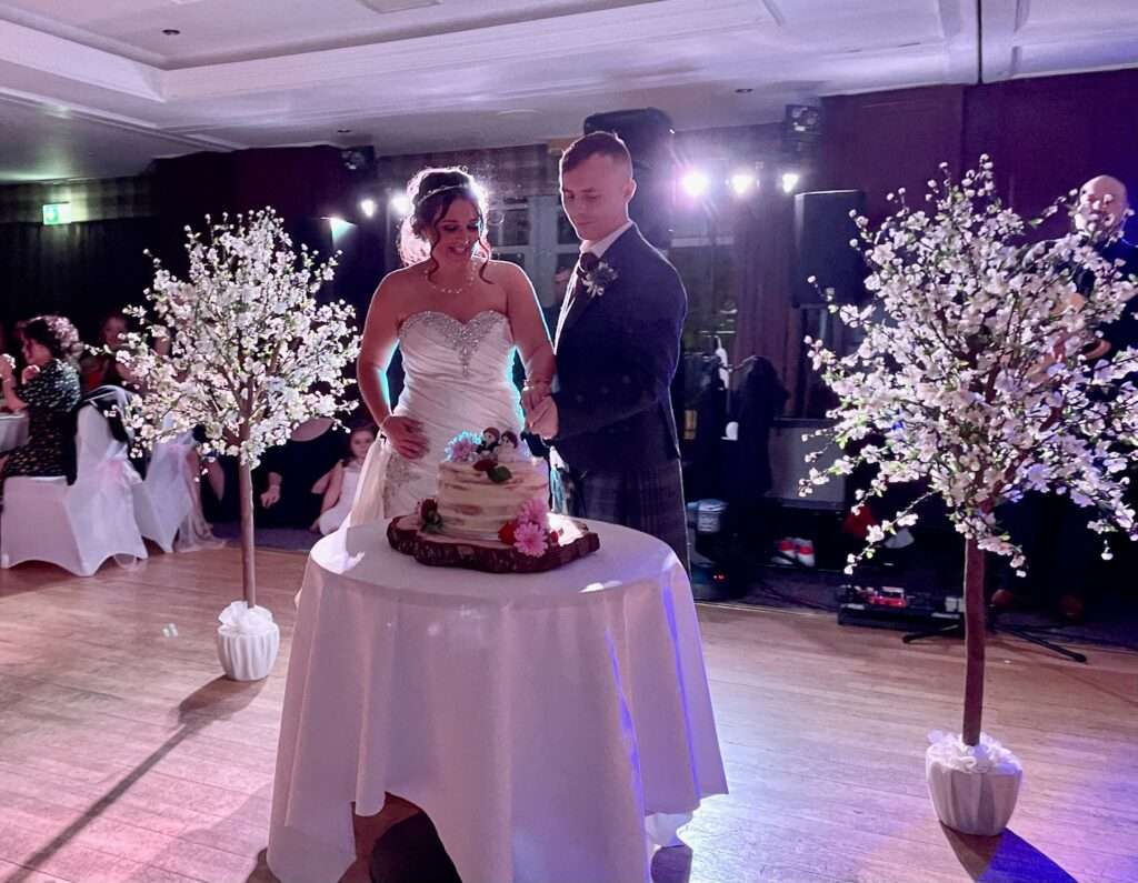 Bride and groom Aimee & Stuart McCandells cutting wedding cake with fife best wedding band the dirty martinis